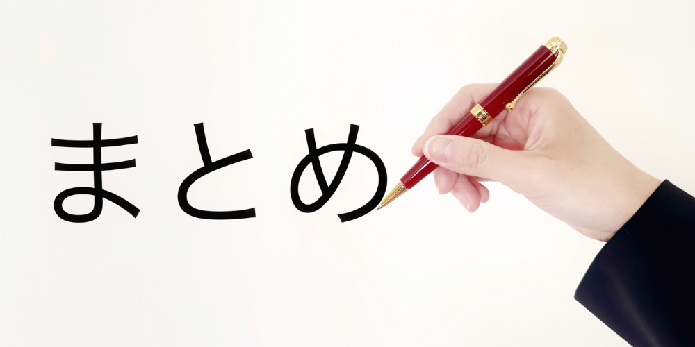 「まとめ」と大きく書かれた白背景を、赤いボールペンを持つ手が指し示しているイメージ