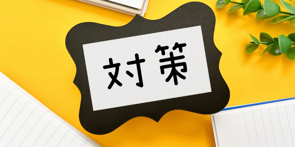 黄色い背景に「対策」と書かれたカードとノート、グリーンを並べたイメージ