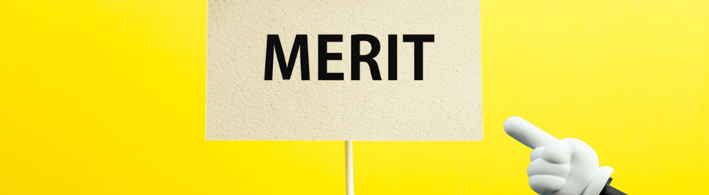 木目背景に「DEMERIT」と書かれた文字と人の指先