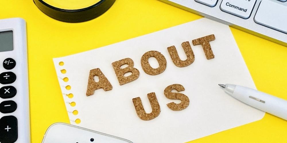 ノートと文房具の上に「ABOUT US」