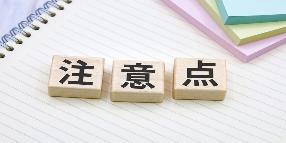 ノートの上に置かれた『注意点』の木製ブロックと付箋のイメージ