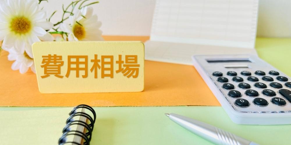 「費用相場」と書かれた札と電卓、ノート、ペンのイメージ