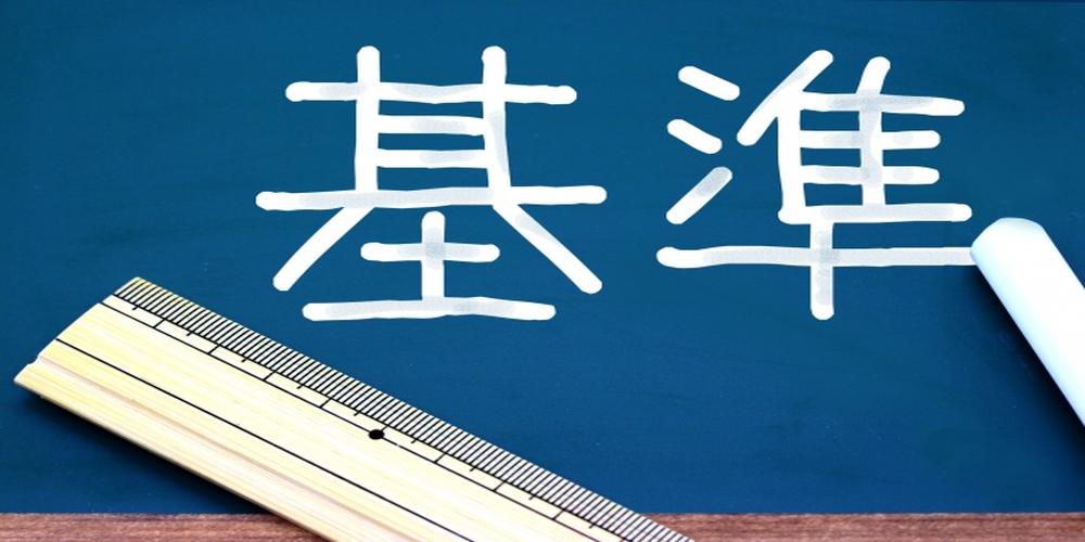 黒板に書かれた『基準』の文字と定規・チョークのイメージ