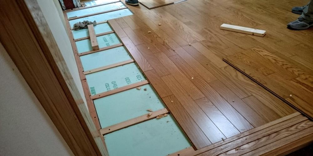 住宅リフォームにおける床材の張り替え作業。断熱材とフローリング施工のプロセスを示す