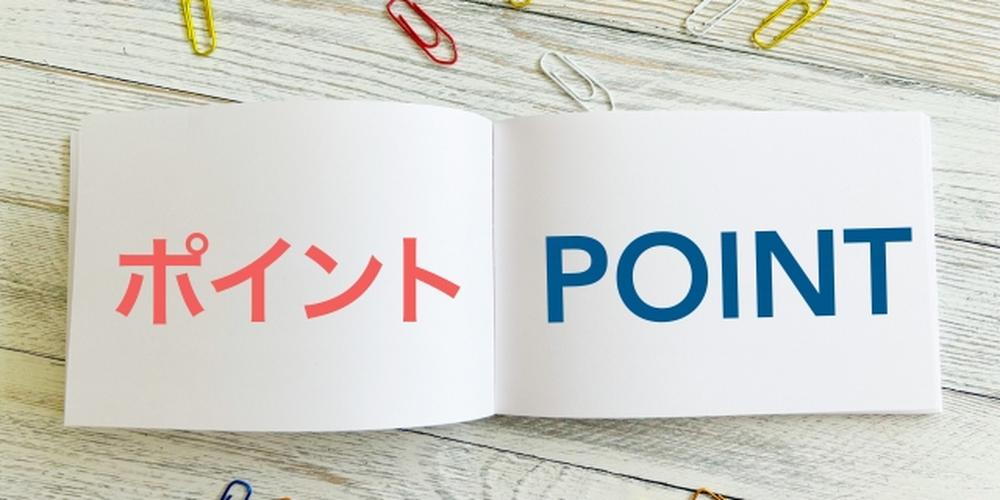 白い本に「ポイント」「POINT」と書かれた文字と散らばるカラフルなクリップ