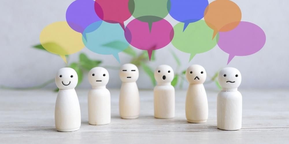 表情の異なる木製人形と、カラフルな吹き出しが並んでいるイメージ