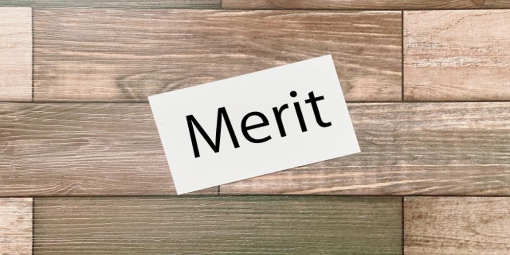ALT　木目調の背景に置かれた『Merit』と記されたカード、サービスや製品の利点を示すシンプルなビジュアル表現