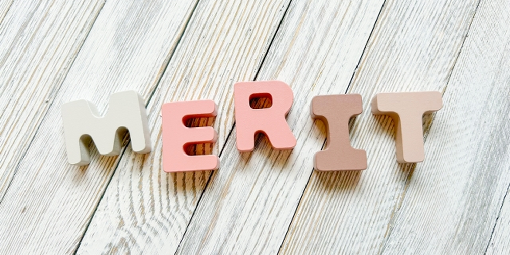 木目調の背景に並べられた“MERIT”の立体文字