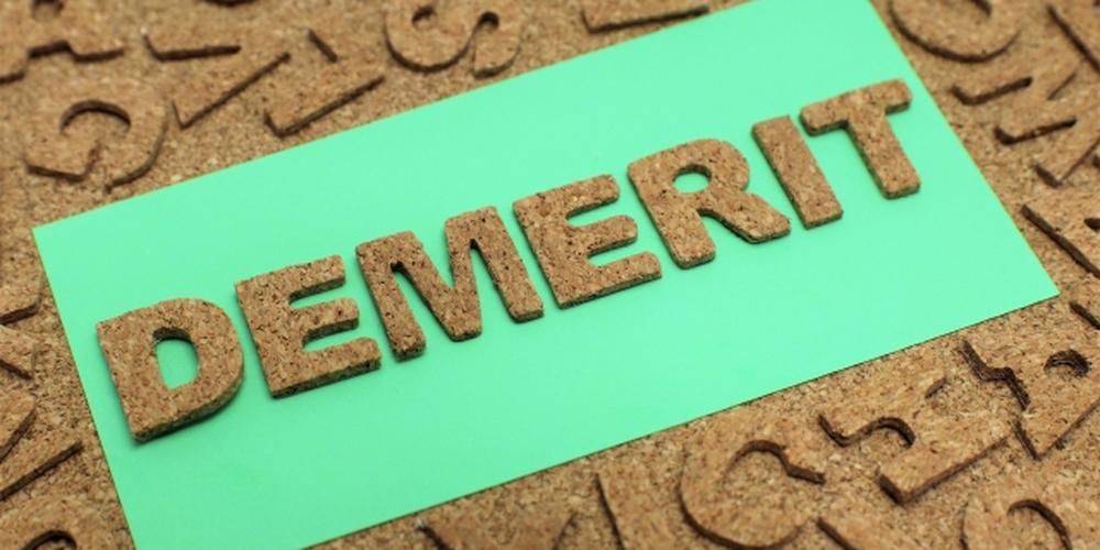 緑色の紙の上にコルク素材で「DEMERIT」と文字が並べられた画像