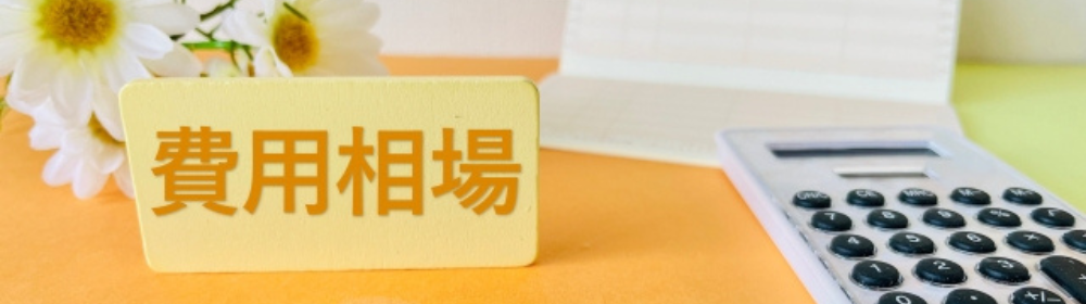 「費用相場」と書かれた札と電卓、通帳、白い花が並べられたイメージ