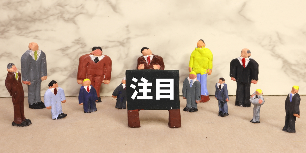 「 注目」の黒板を囲むスーツ姿のミニチュア人形たち