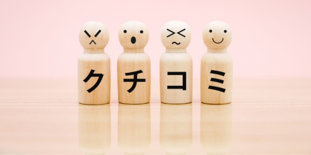 異なる表情の木製人形に「クチコミ」の文字が書かれたイメージ