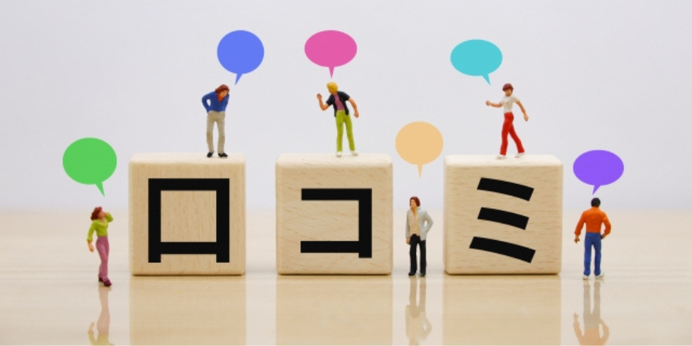 吹き出しを持ったミニチュア人形たちと「口コミ」の積み木が並ぶイメージ