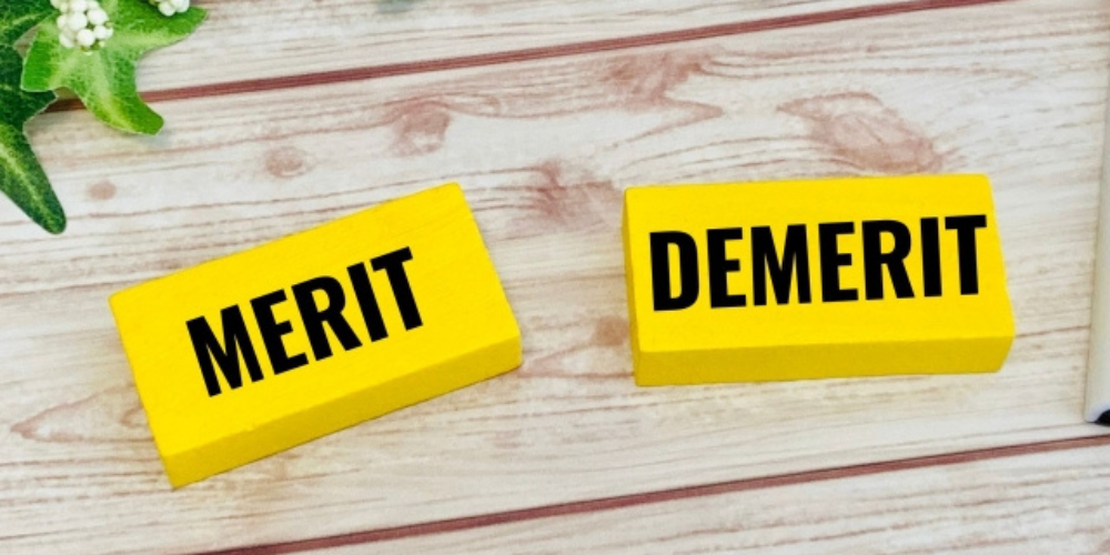 木目の背景に「MERIT」「DEMERIT」と書かれた黄色いブロックが置かれているイメージ