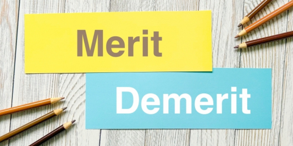 木目背景に「Merit」「Demerit」と書かれたカードと色鉛筆が並ぶ比較イメージ